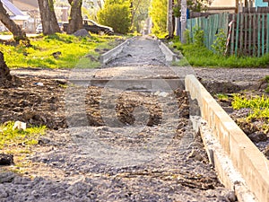 Curb installation and sidewalk construction outside the city, selective focus