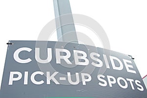 curbside pick up spots sign on post with building and sky in background. Ph
