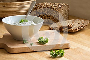 curd cheese dip with herbs in a bowl and rustic bread in the background