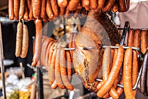 Cured meat products such as ham, sausages and frankfurters hanging at the market vendor booth outdoors