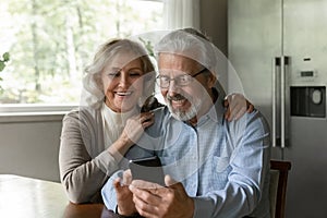 Curious aged wife watch husband playing game on mobile phone