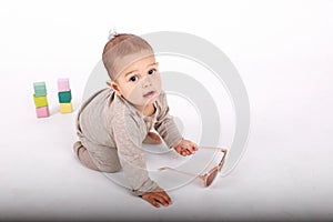 Curious baby boy in cream clothes playing with sunglasses