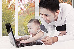 Curious baby with dad playing laptop