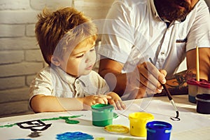 Curious beautiful child watches his father draw. Curious boy. Early development. Education. Drawing for children. School
