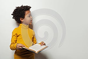 Curious black child boy reading a book on white background