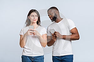 Curious Black Man Spying And Peeking At Smartphone Of His Girlfriend