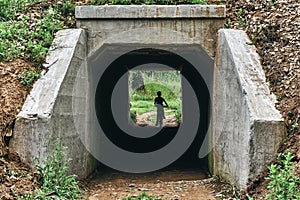 Curious boy on a bike rides into a dark tunnel under the railway