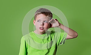 Curious boy listens. Closeup portrait child hearing something, parents talk, gossips, hand to ear gesture isolated on green.