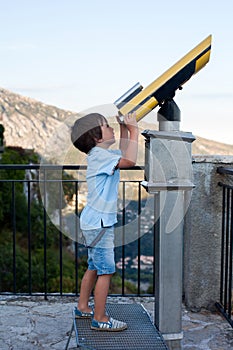 Curious boy, looking through a telescope at something interesting