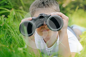 Curious boy looks for wildlife through binoculars in the park. Exploring the world, bird watching. Outdoor activities. boy looking