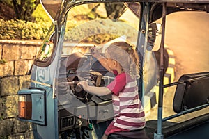 Curious child mechanic girl driving tuk tuk motorbike during travel Asia Thailand concept children travel lifestyle