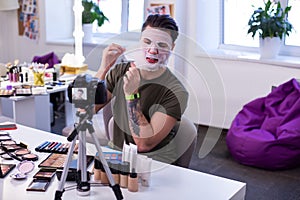 Curious communicative guy sitting in front of professional camera