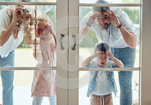 Curious couple with little kids standing and peering into their new home. Excited smiling caucasian family looking at