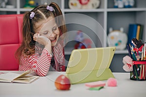 Curious cute preschool kid girl using digital tablet technology device. Small child hold pad computer surfing internet