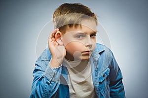 Curious Disappointed boy listens. child hearing something, hand to ear gesture