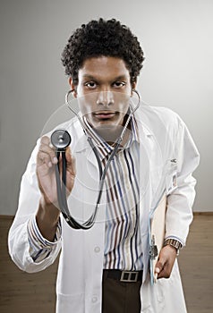 Curious doctor in lab coat holding stethoscope