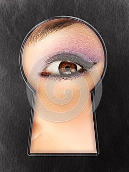 Curious female eye in a keyhole