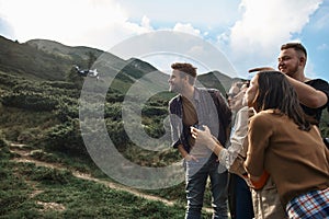 Curious friends smiling and looking at the flying dron photo