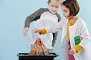 Curious girl in white robes doing chemical volcano experiment with a boy