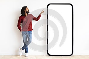 Curious hindu guy pointing at huge phone with blank screen