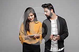 Curious indian boyfriend is spying his lovers smartphone standing isolated on gray background