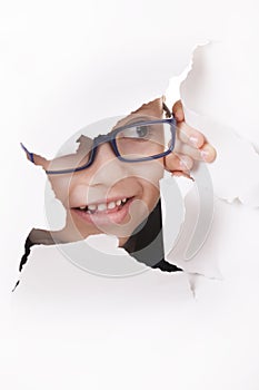 Curious kid looks through a hole in paper