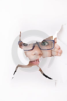 Curious kid looks through a hole in paper