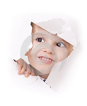 Curious kid looks through a hole in white paper