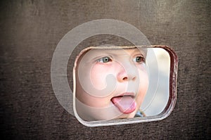 Curious kid spying through the hole in the wooden wall on playground