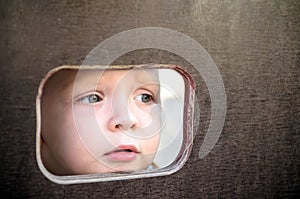 Curious kid spying through the hole in the wooden wall on playground