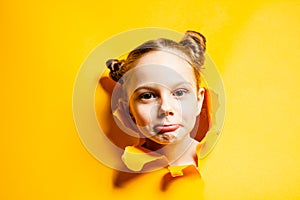 Curious little girl looking through hole in yellow paper. Seasonal sales and discounts.