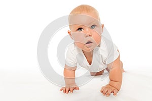 Curious looking baby crawls wearing white bodysuit