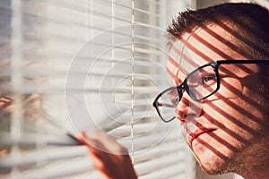 Curious man looking through a jalousie