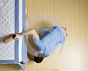 Curious man peering underneath bed