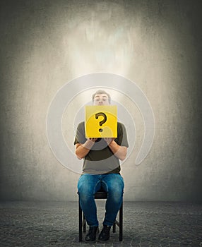 Curious man sitting on a chair looking cautious inside a mysterious yellow box as a magic light comes out photo