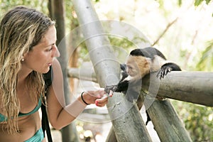 Curious monkey holding woman hand in forest