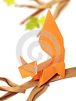 Curious origami cartoon squirrel on a branch on a white