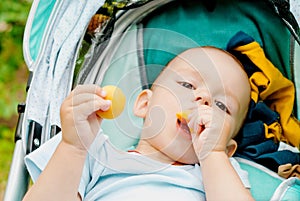 Curious and playful baby boy eating an apricot