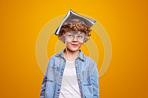 Curious pupil with textbook on head