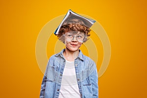 Curious pupil with textbook on head photo