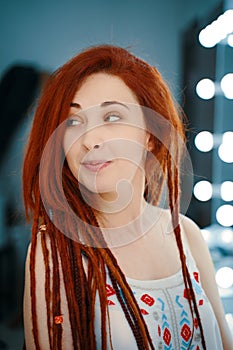 Curious red-haired girl with long dreadlocks.