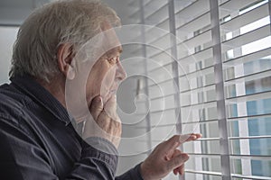 Curious senior man looking at the window