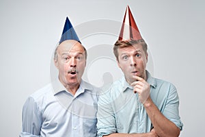 Curious shocked men, standing in casual shirts, isolated on pure background with wonderment. photo