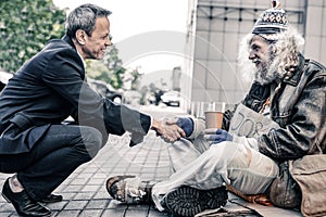 Curious short-haired businessman sitting in front of long-haired homeless