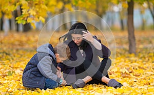 Curious son with mother in a park with fall leaves.