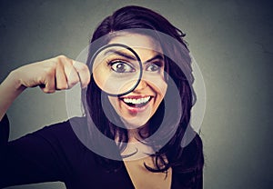 Curious surprised young woman looking through a magnifying glass