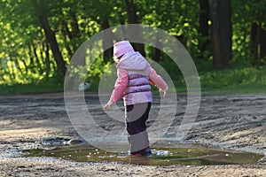 Curious toddler girl walking in summer puddle