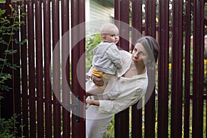 Curious woman with a baby peeps openint the gate of fence