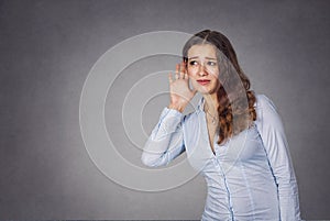 Curious woman with hand to ear carefully listening to gossip con