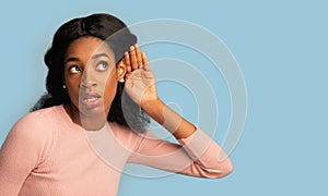 Curious young black female with hand near ear trying to overhear something